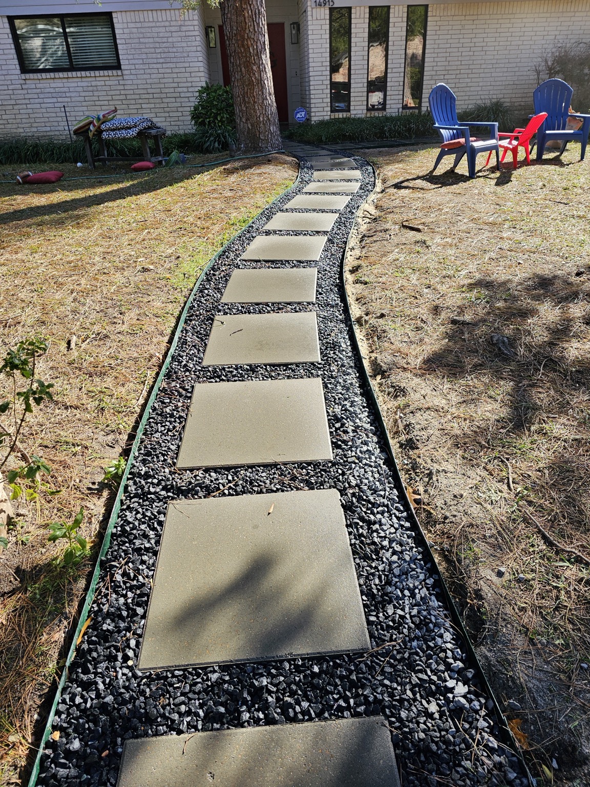 After view of a curved stepping-stone walkway with dark decorative gravel in Houston, Texas